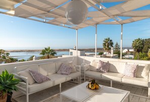 A covered outdoor seating area with white furniture and a view of the sea. - Fabrica Beach Apartamentos (Vila Real Santo Antonio)