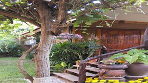 A garden with a wooden staircase, potted plants, and a large door. - Orchid Homestay Buriram No1 (Phlapphlachai)