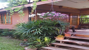 A wooden house with a porch, potted plants, and a staircase leading to the entrance. - Orchid Homestay Buriram No1 (Phlapphlachai)