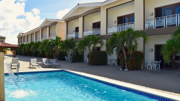 Un hôtel doté d’une piscine, de chaises longues et de palmiers.