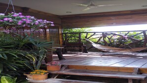A wooden deck with a hammock, wooden benches, and potted plants. - Orchid Homestay Buriram No2 (Phlapphlachai)