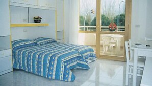 Een slaapkamer met een bed, een klein tafeltje en een raam met uitzicht.