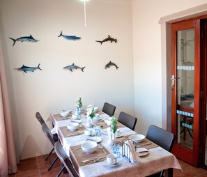 Zona pranzo con tavolo apparecchiato per quattro, sedie e decorazioni a tema squali.