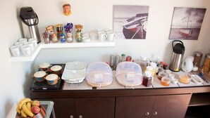 Ein Frühstücksbuffet mit verschiedenen Speisen, Tassen und Behältern.