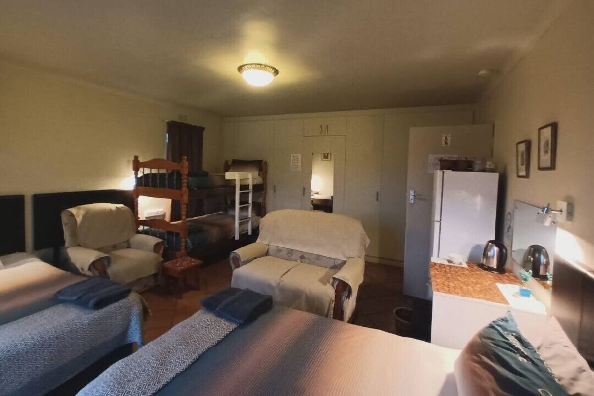 A hotel room with two beds, a sofa, a chair, a small table, and a refrigerator.