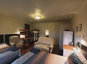 Une chambre d’hôtel avec deux lits, un canapé, une chaise, une petite table et un réfrigérateur.
