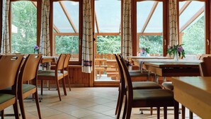 A dining area with wooden furniture and large windows. - Oko-Park Panzió Kemping és Rendezvényközpont (Szarvasko)