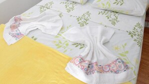 A bed with floral bedding and a yellow blanket. - Pousada LN (Caldas Novas)