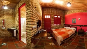 A room with a brick wall, a bed, a red door, a sink, and a mirror. - Oh Linda Pousada (Icapuí)