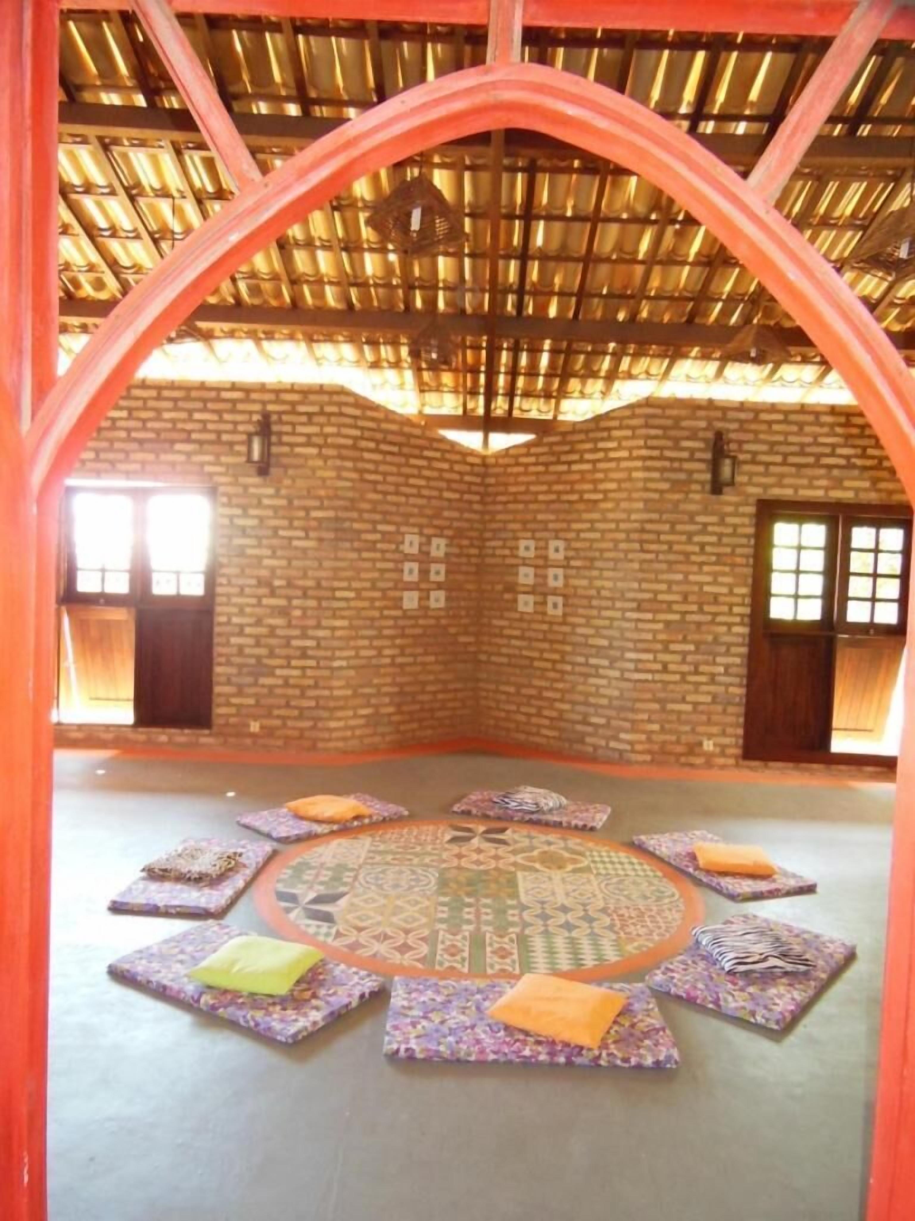 Una habitación con pared de ladrillo, techo de madera y un tapete circular con estampado en el suelo.