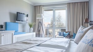 Een hotelkamer met een bed, een televisie, een bureau met lamp en uitzicht op het omliggende landschap.