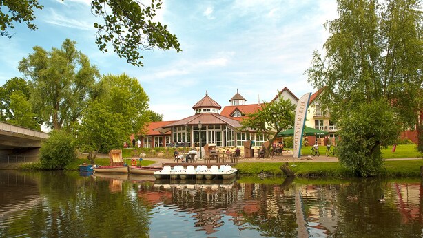 Hotel aan de rivier met een steiger, terras en uitzicht op het water.