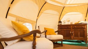 A tent with two wooden beds, each with white and yellow pillows, and a wooden cabinet with a mirror and small items on top. - Wild Lotus Glamping (Bequia Island)