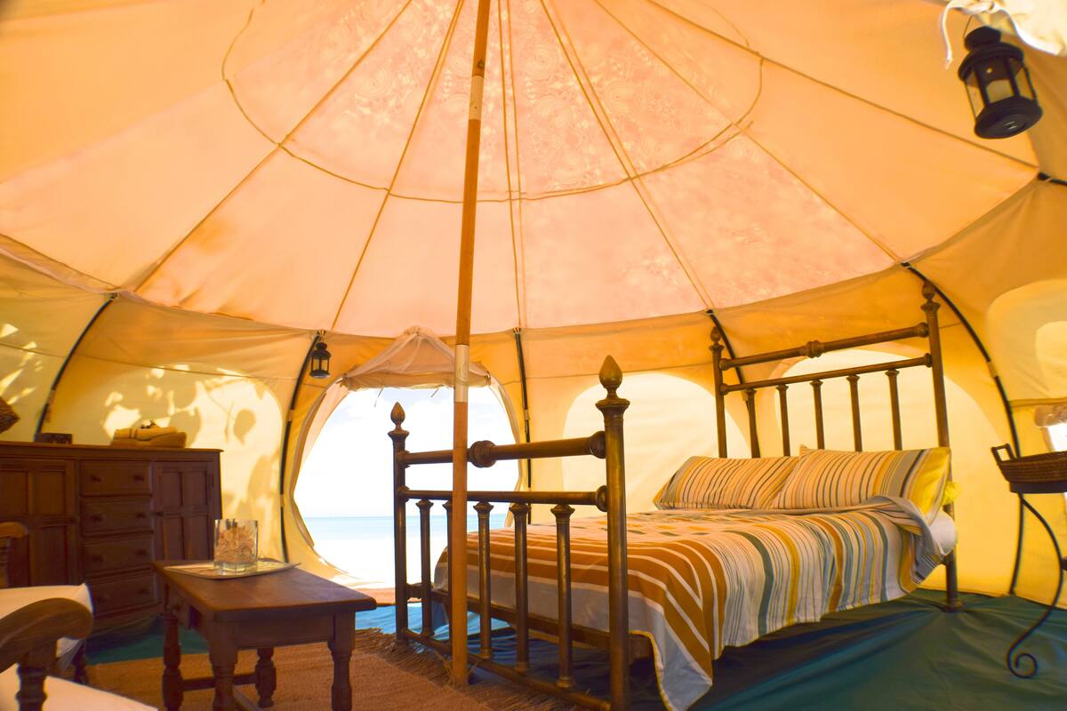A tent with a bed, a dresser, and a table.
