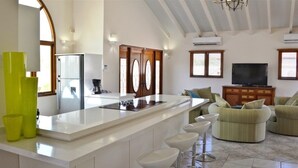 Une cuisine moderne dotée d’un îlot central, de tabourets de bar et d’un coin salon avec des fauteuils confortables.