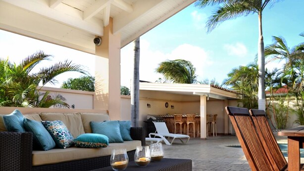 Une terrasse extérieure aménagée avec un canapé, des fauteuils de relaxation, un coin repas et une piscine.