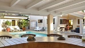 Un espace piscine extérieur doté d’un sol carrelé, de chaises longues et d’un coin salon abrité.