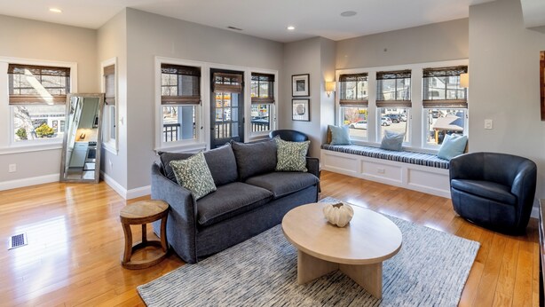 A spacious living room with a grey sofa, a round coffee table, and a black armchair. - The Newport Lofts - 595 Thames Street (Newport)