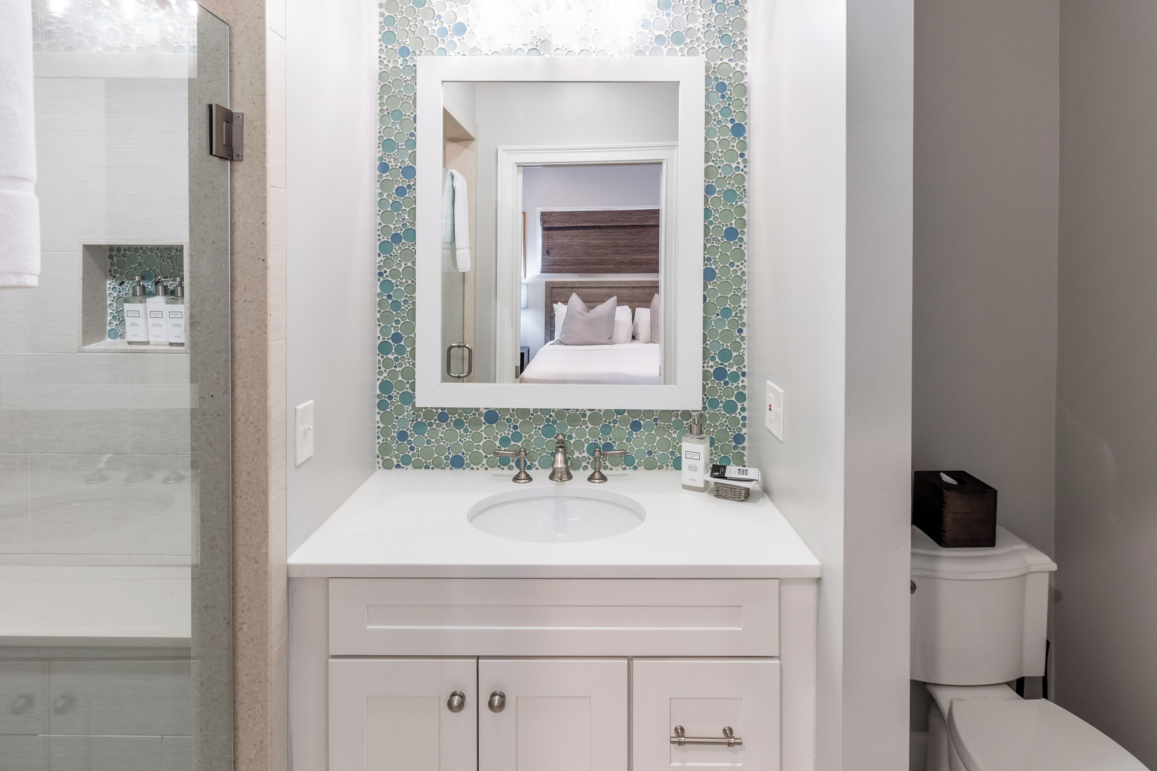 A bathroom with a white sink, a mirror, and a toilet.