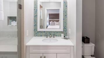 A bathroom with a white sink, a mirror, and a toilet.