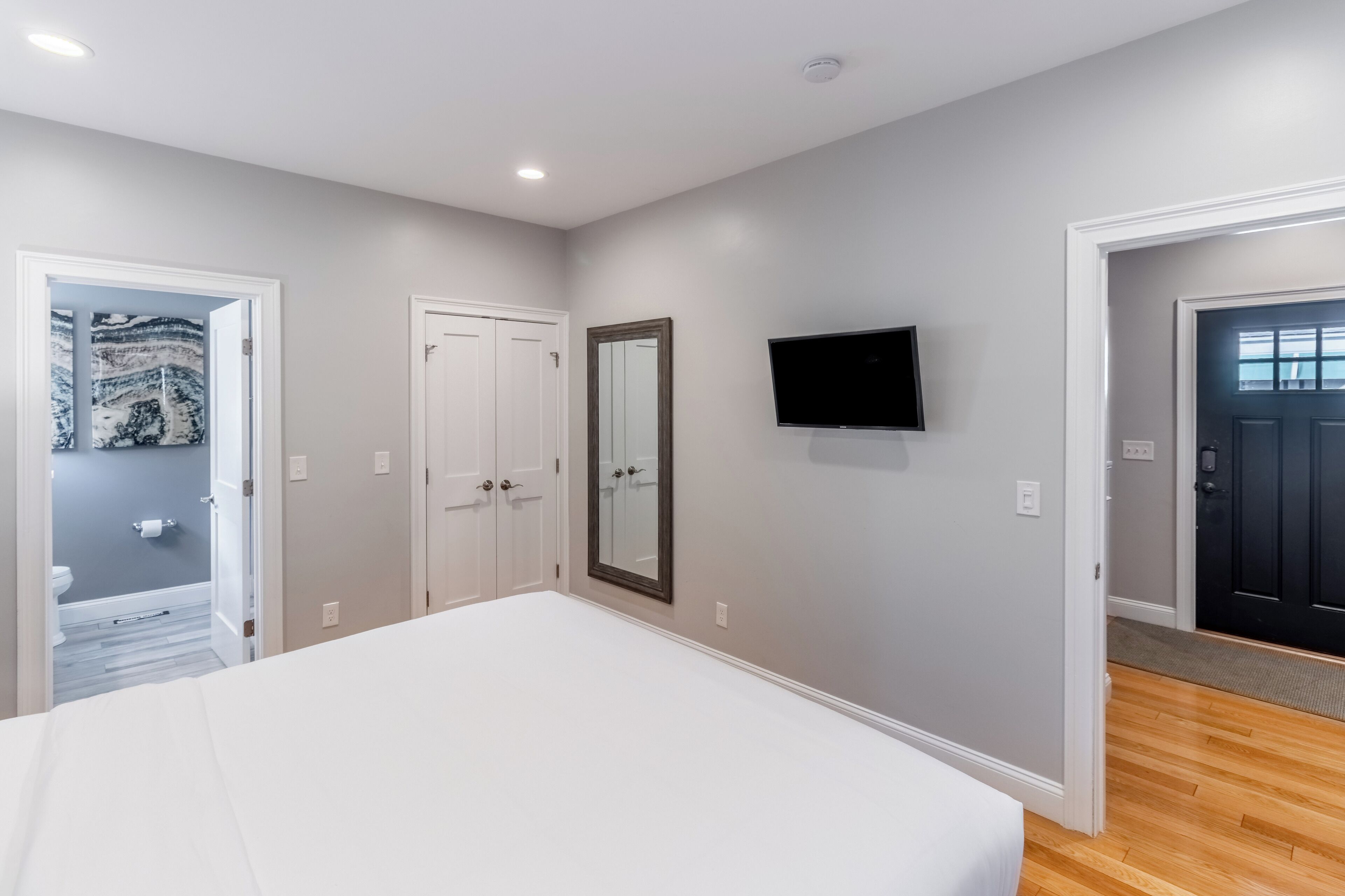 A bedroom with a bed, a television, and a door leading to a bathroom.
