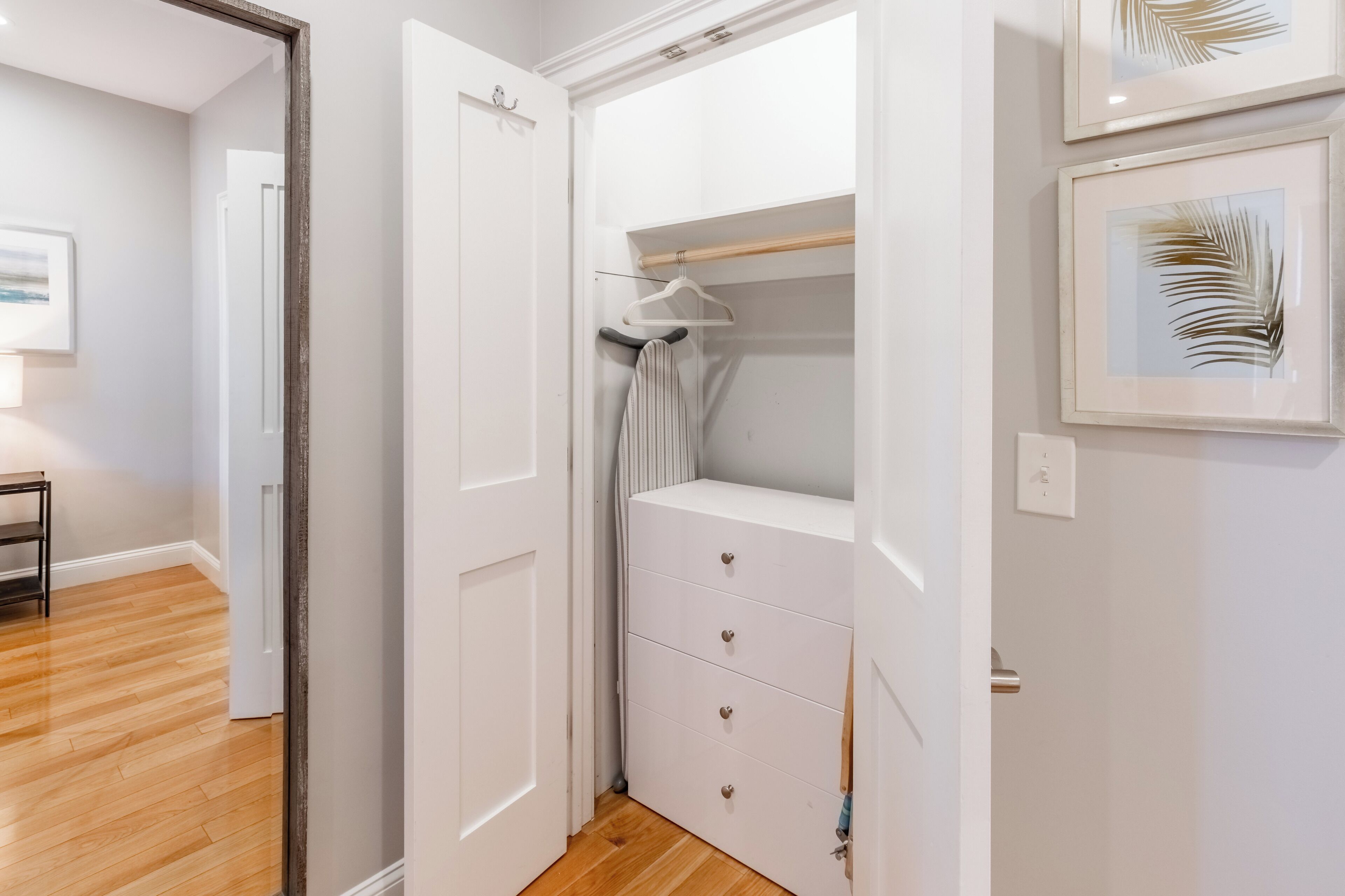 A walk-in closet with a white dresser and hanging space.