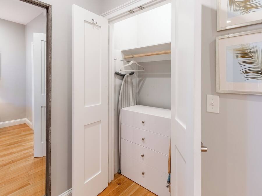 A walk-in closet with a white dresser and hanging space.