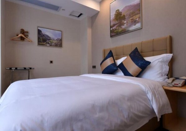 A hotel room with a large bed, a bedside table with a phone, and two paintings on the wall. - Days Inn Business Place Bagu Chongqing (Chongqing)