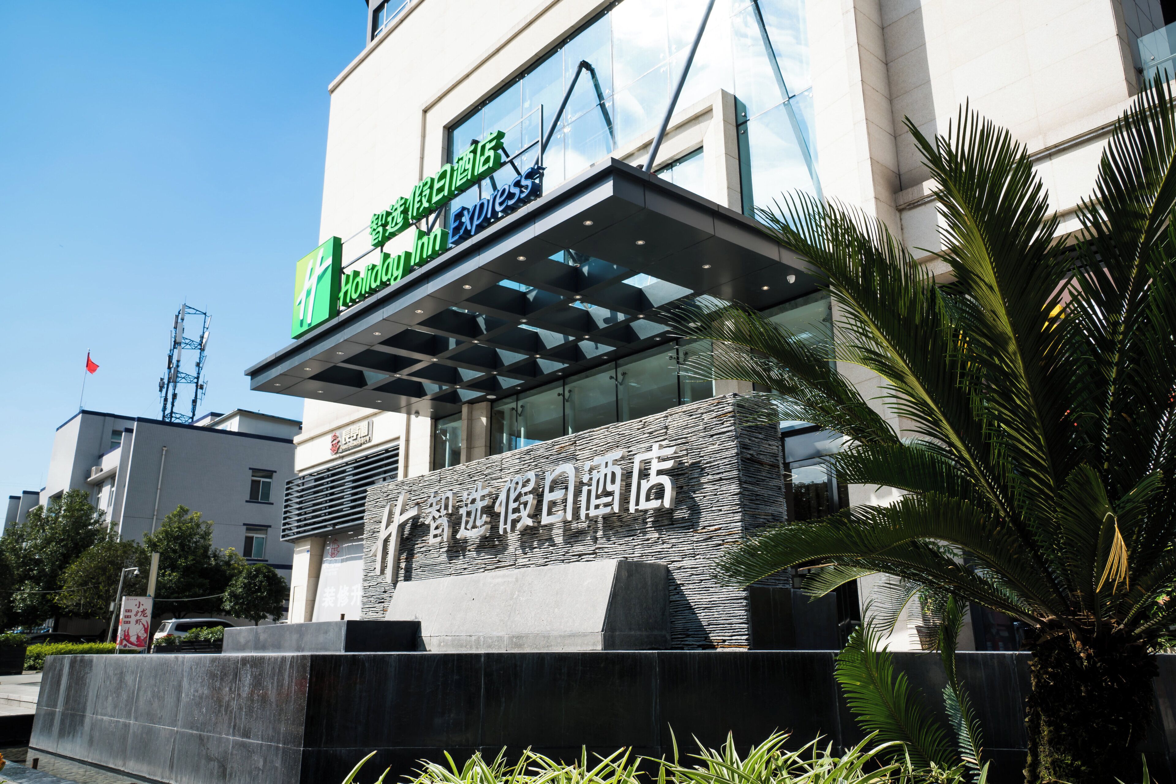 A hotel with a modern facade, a prominent sign for Holiday Inn Express, and a stone-textured entrance.
