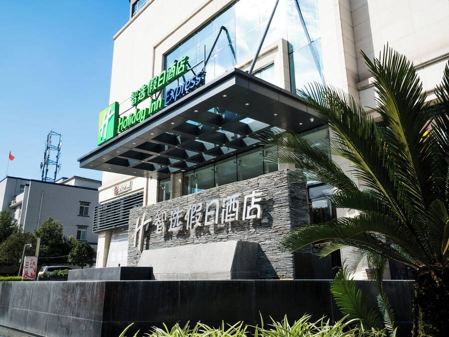 A hotel with a modern facade, a prominent sign for Holiday Inn Express, and a stone-textured entrance.
