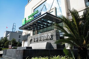 A hotel with a modern facade, a prominent sign for Holiday Inn Express, and a stone-textured entrance. - Holiday Inn Express Chengdu Xindu by IHG (Chengdu)