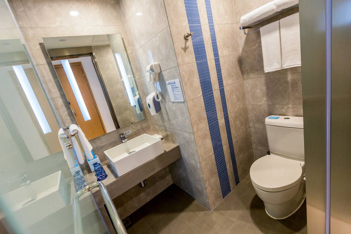 A bathroom with a sink, mirror, towel rack, and toilet.