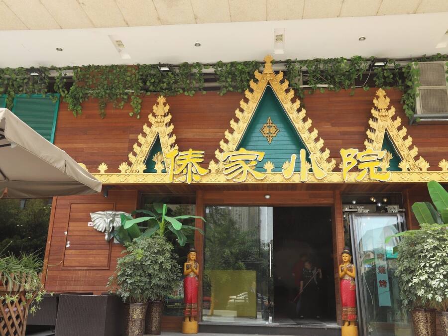 Entrada de un edificio tradicional tailandés con decoraciones doradas ornamentales y techo verde.