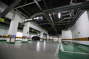 Eine mehrstöckige Parkgarage mit Hinweisschildern, Betonsäulen und einem grünen Stellplatz.