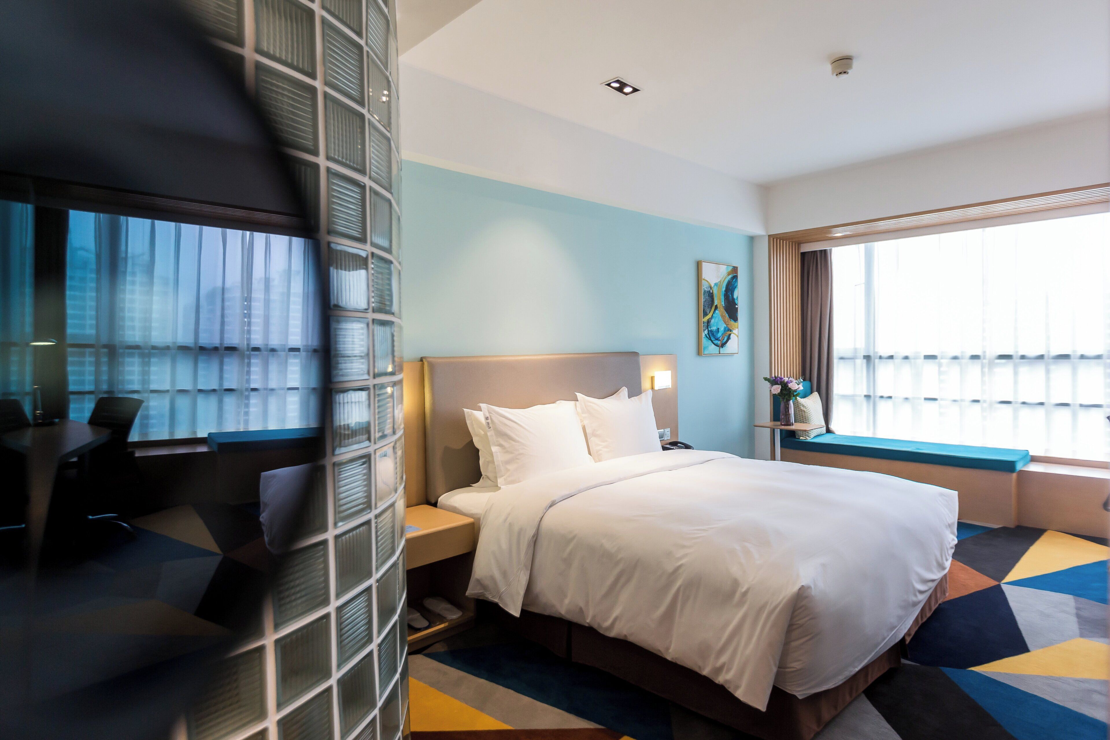 Una habitación de hotel con cama, escritorio y ventana.