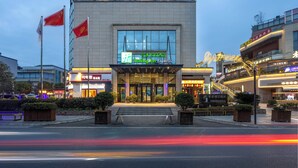 A hotel with a modern facade, large glass windows, and a prominent entrance with steps. - Holiday Inn Express Chengdu Xindu by IHG (Chengdu)