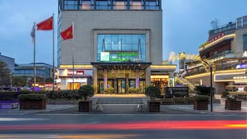 Un hotel con fachada moderna, amplios ventanales de vidrio y una entrada destacada con escalones.