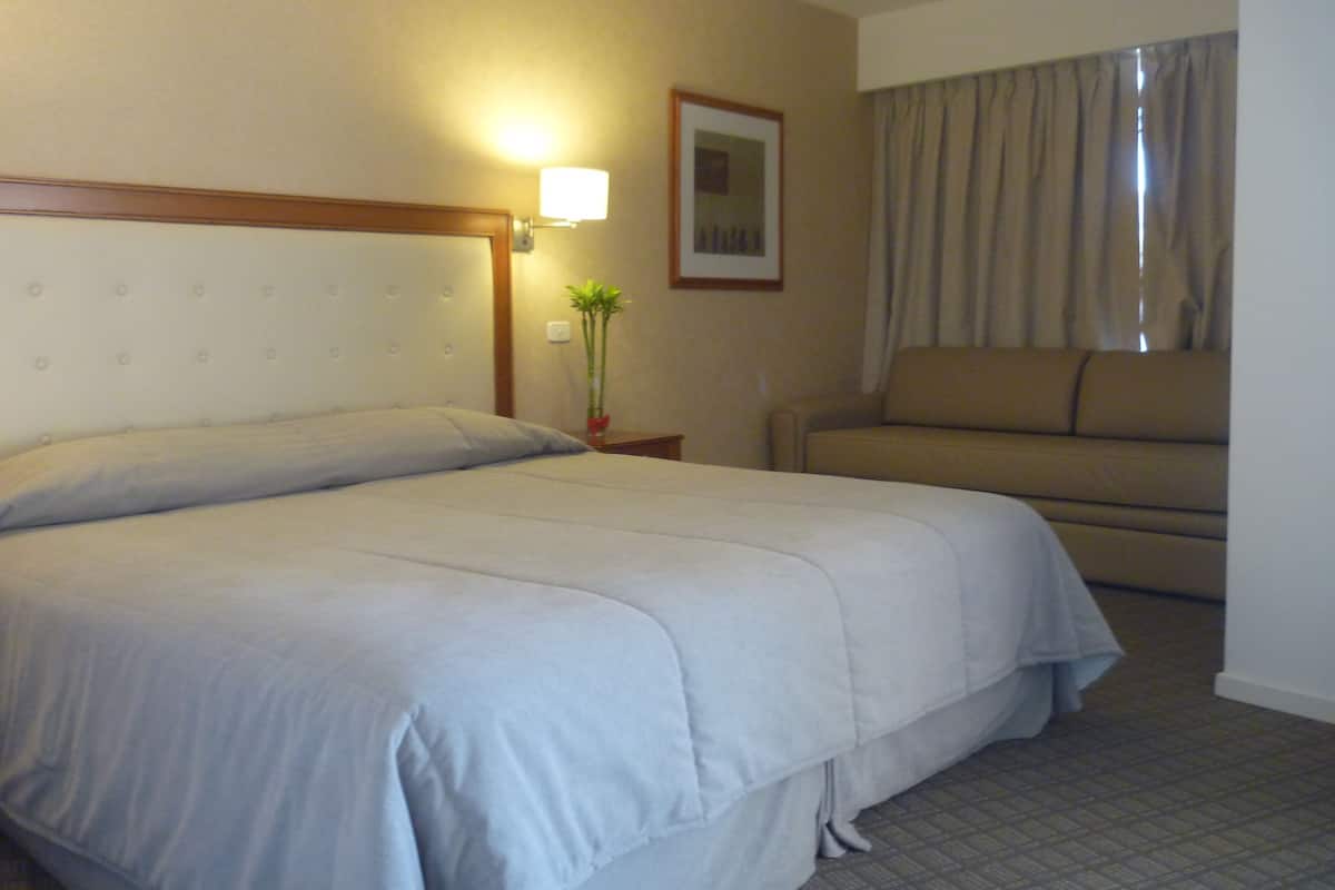 Une chambre d’hôtel avec un grand lit, un canapé, une lampe et un tableau encadré au mur.