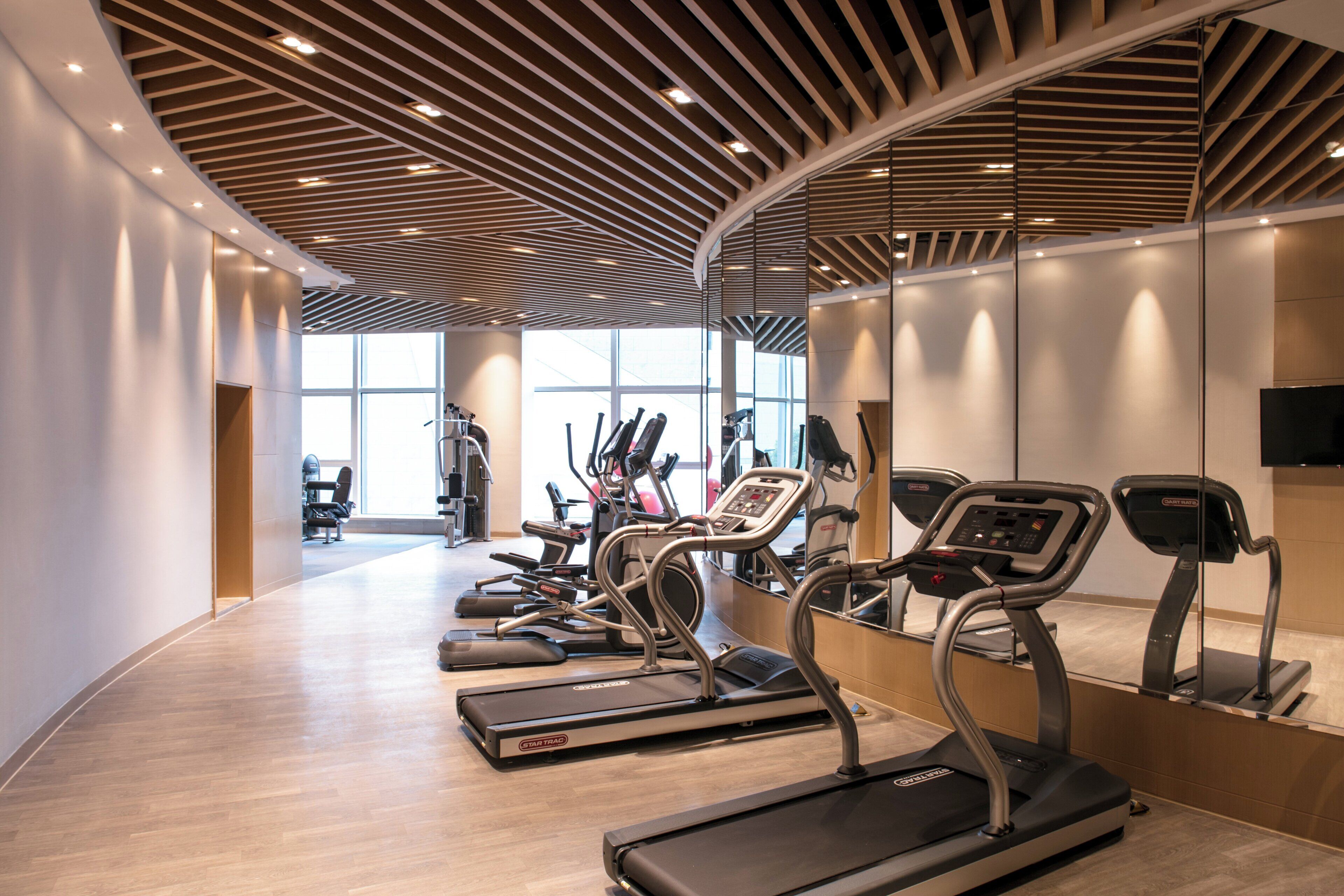 Un gimnasio moderno con cintas de correr, bicicletas estáticas y pesas libres.