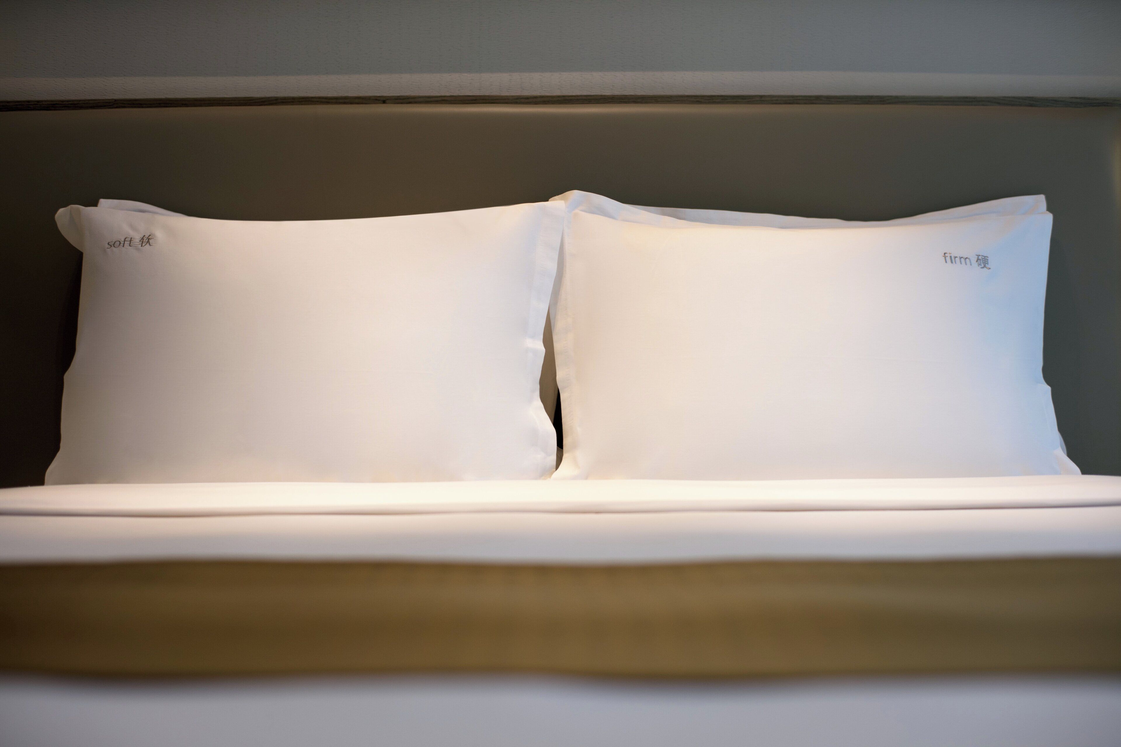 A neatly made bed with two white pillows and a headboard.