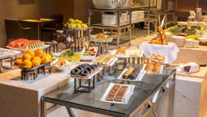 A buffet with various food items and a seating area with chairs and a table. - Holiday Inn Hangzhou Gongshu by IHG (Hangzhou)