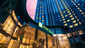 A modern hotel with a curved facade, large windows, and a prominent sign. - Holiday Inn Hangzhou Gongshu by IHG (Hangzhou)