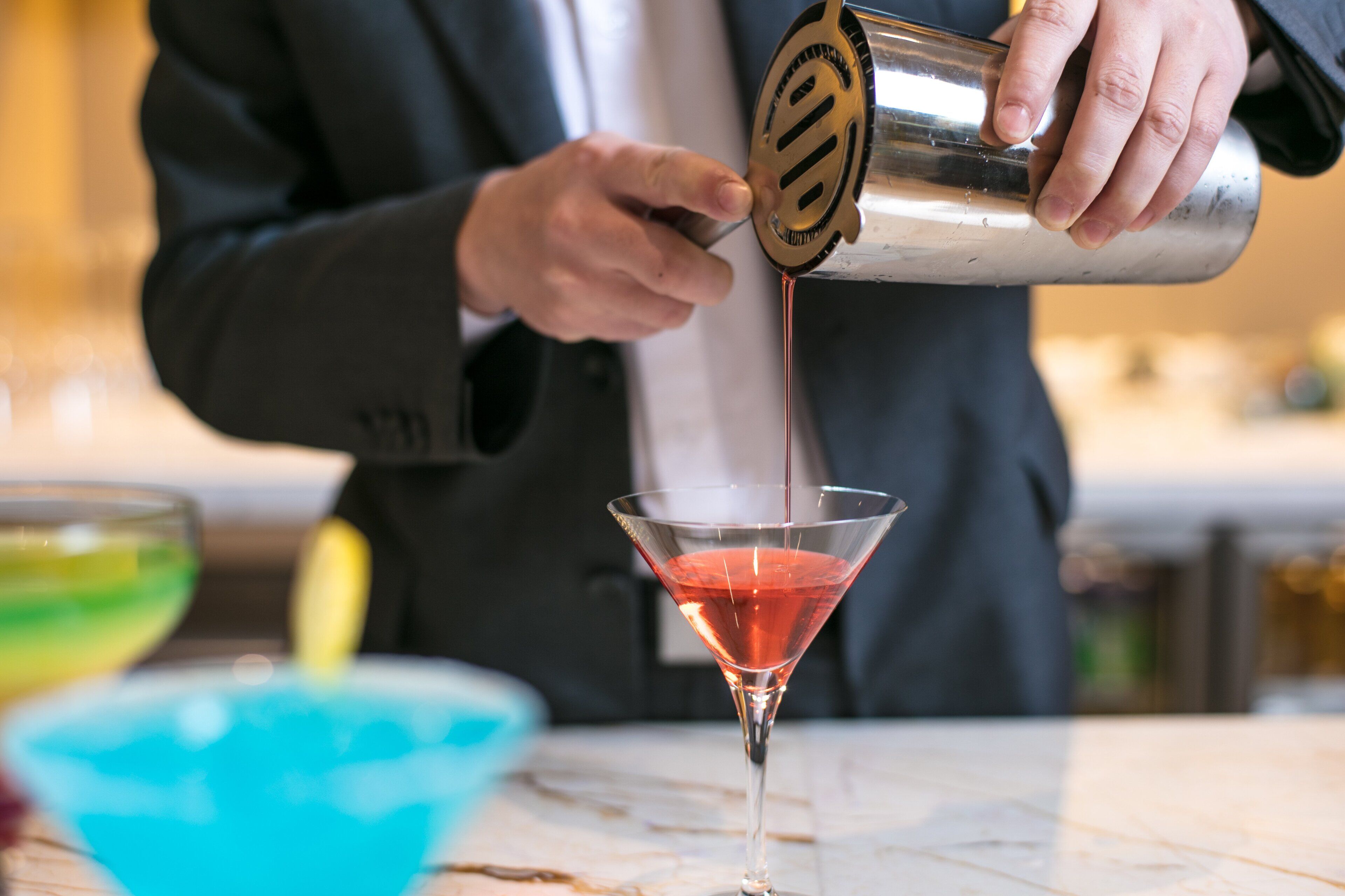 A person pouring a drink into a martini glass.