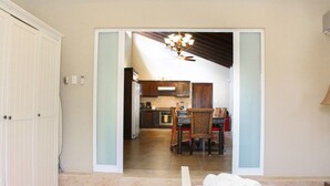 A room with a bed, a window, and a view of a dining area with a table and chairs. - Casa Luna (Oranjestad)