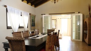 A dining area with a dark wooden table, wicker chairs, and a chandelier. - Casa Luna (Oranjestad)