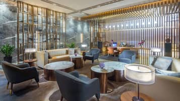 A modern lounge area with seating, tables, and a decorative wall.