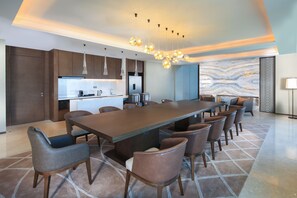Une cuisine moderne dotée d’un grand îlot central, de luminaires suspendus et d’un pare-feu en marbre.