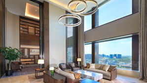 A spacious living area with a large window offering a city view, a modern chandelier, and a cozy seating arrangement. - Intercontinental Taiyuan by IHG (Taiyuan)