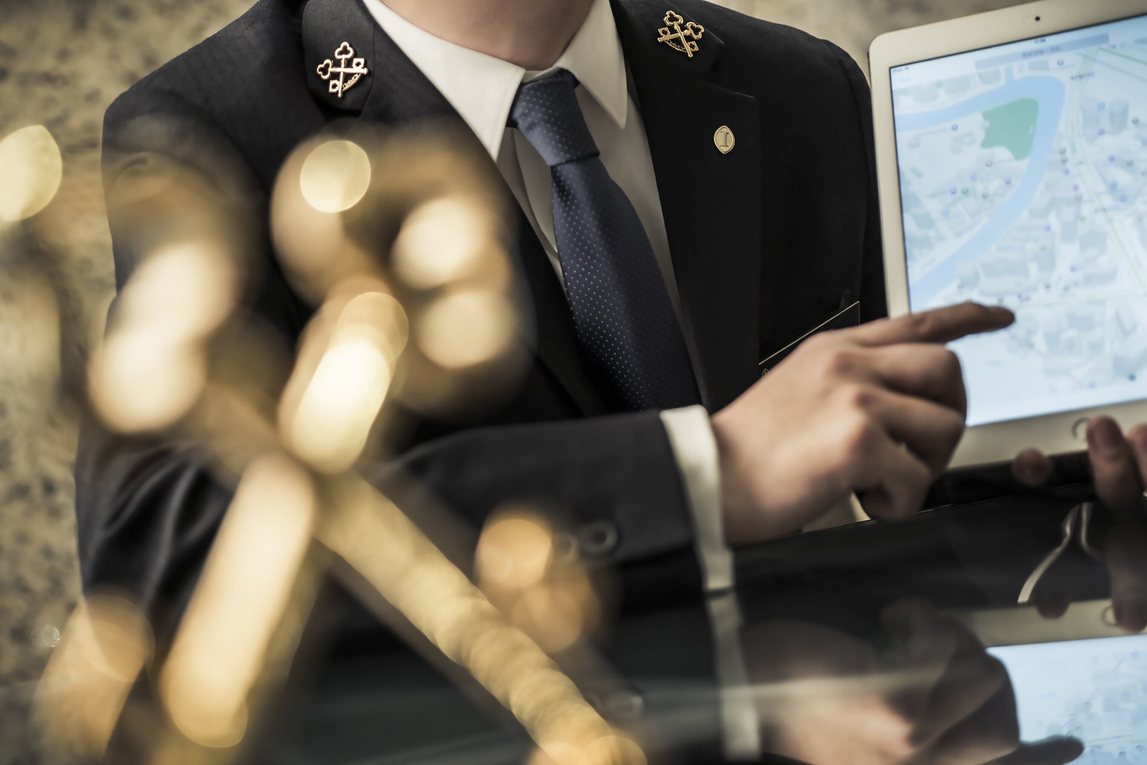 A person in a suit pointing at a tablet displaying a map.