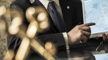A person in a suit pointing at a tablet displaying a map.